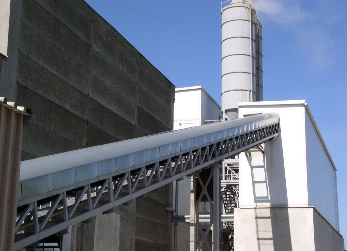 Zewnętrzny przenośnik taśmowy prowadzący do silosu w zakładzie produkcyjnym